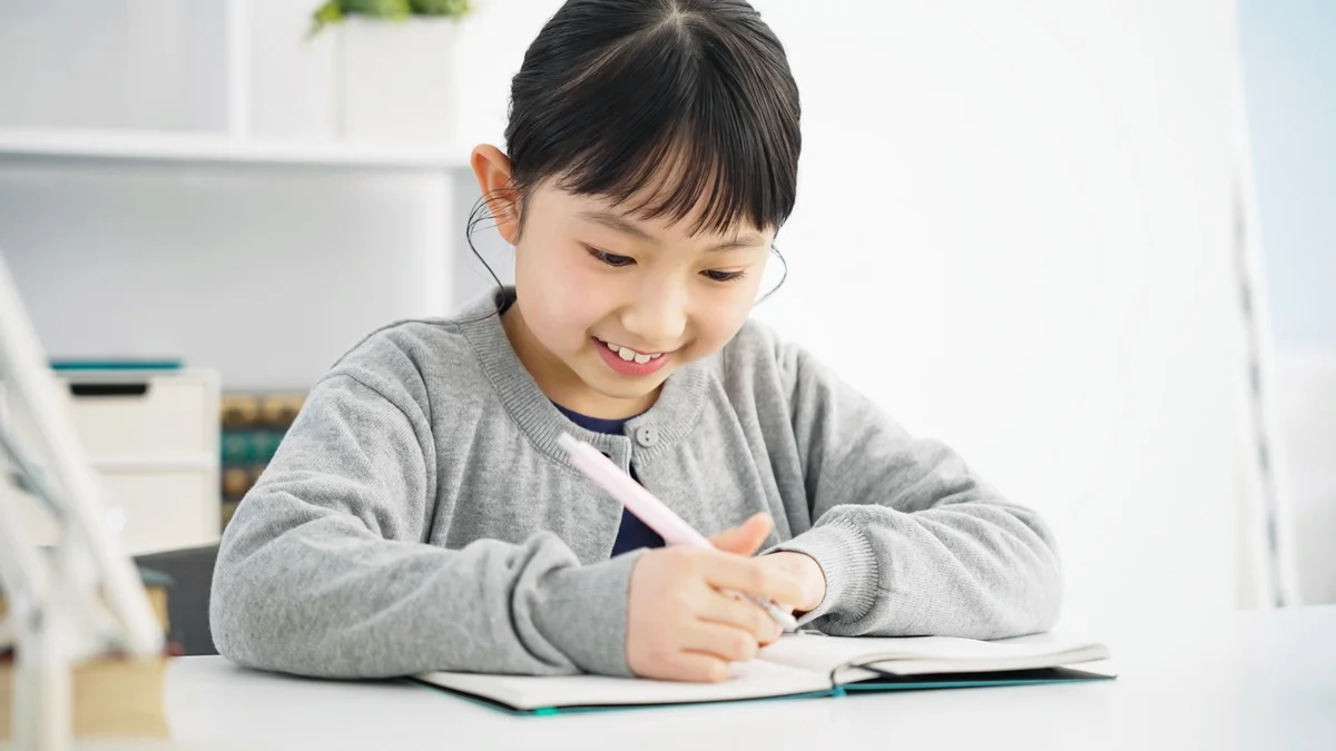 ノートに英語を書く女の子